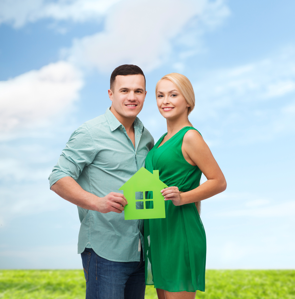 real estate, family and couple concept - smiling couple holding green paper house